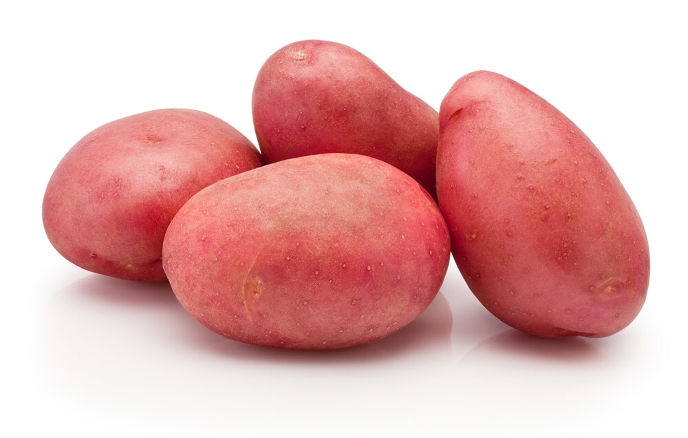 Four fresh red potatoes on white background.
